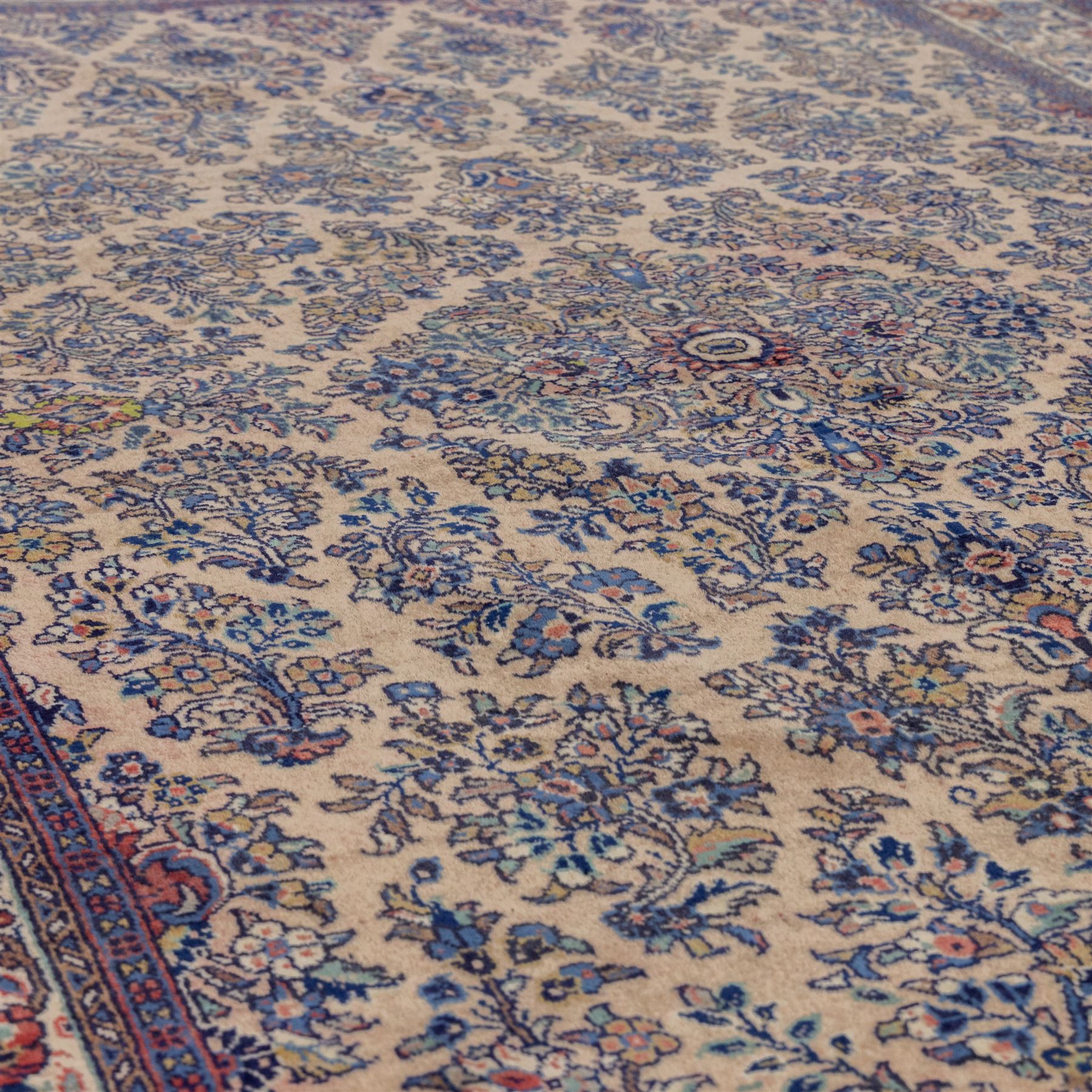Central Persian Nain hand-knotted rug, ivory ground decorated with a central lobbed medallion and an all-over floral and foliate design of stylised palmettes, flowering plants, and scrolling vine work, enclosed by a contrasting main border with repeating floral motifs, flanked by multiple guard borders, with cotton fringe ends 