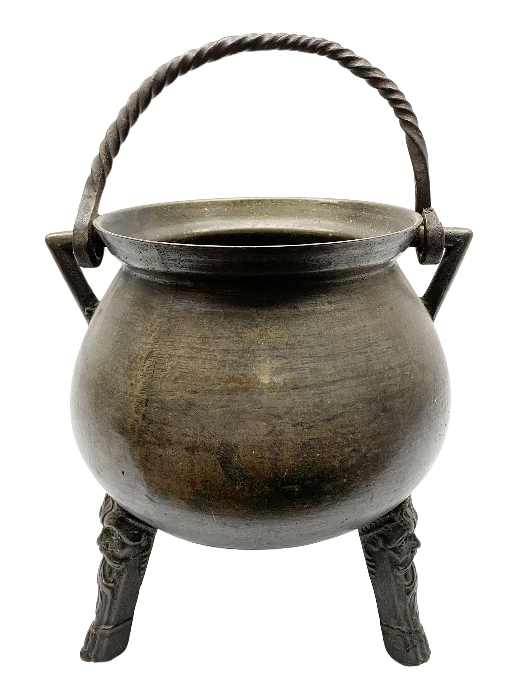 17th century bronze cauldron, probably German or Austrian, of bellied form with twin angular handles supporting a twisted handle, upon three splayed zoomorphic bearded mask feet, not including handle H30cm, rim D22cm