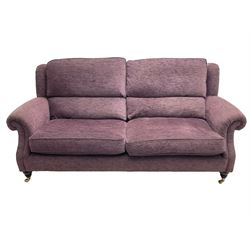 Parker Knoll - pair of large two-seat sofas upholstered in purple fabric, turned mahogany finish front feet with brass cups and castors 