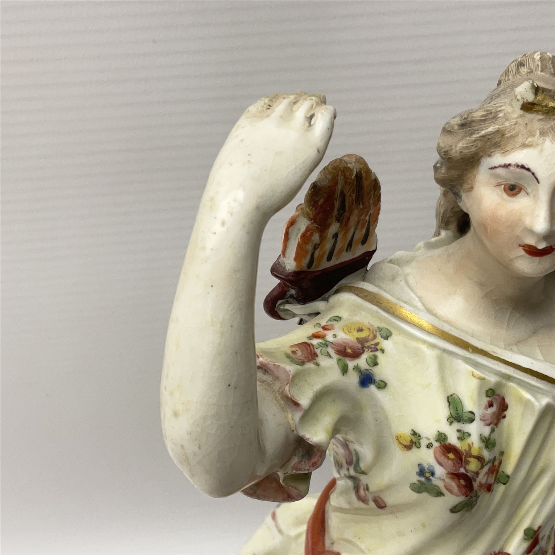 18th century Derby figure of Diana the huntress, circa 1760, modelled reaching for an arrow from quiver across her back, with recumbent hound at her feet, upon a scrolled base with bocage detail, H27.5cm