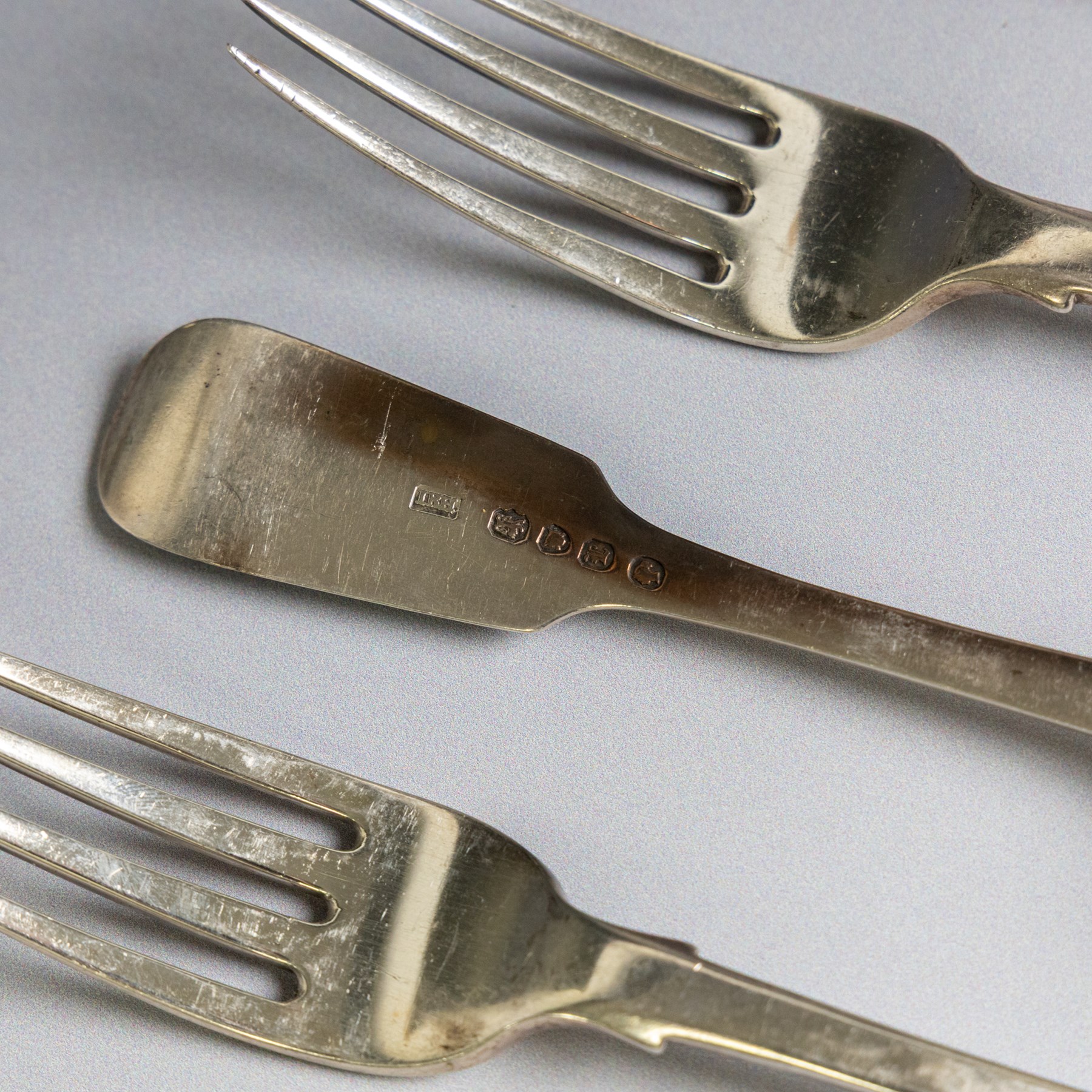 Seven silver Fiddle pattern table forks, comprisng set of four William IV examples, hallmarked William Eaton, London 1836, and three Victorian examples with engraved initials, hallmarked John Robert Harris, London 1846