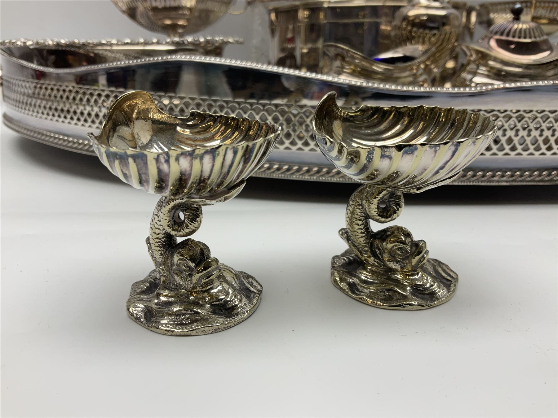 Pair of Mappin and Webb silver plate pierced pedestal bon bon dishes, together with other silver plate comprising teapot stand engraved with lion's head to centre, two cut glass claret jugs, two bottle coasters with acorn decoration, two open salts upon dolphin mounts, tea caddy, three piece cruet set and a large oval tray with pierced sides and upon four ball feet