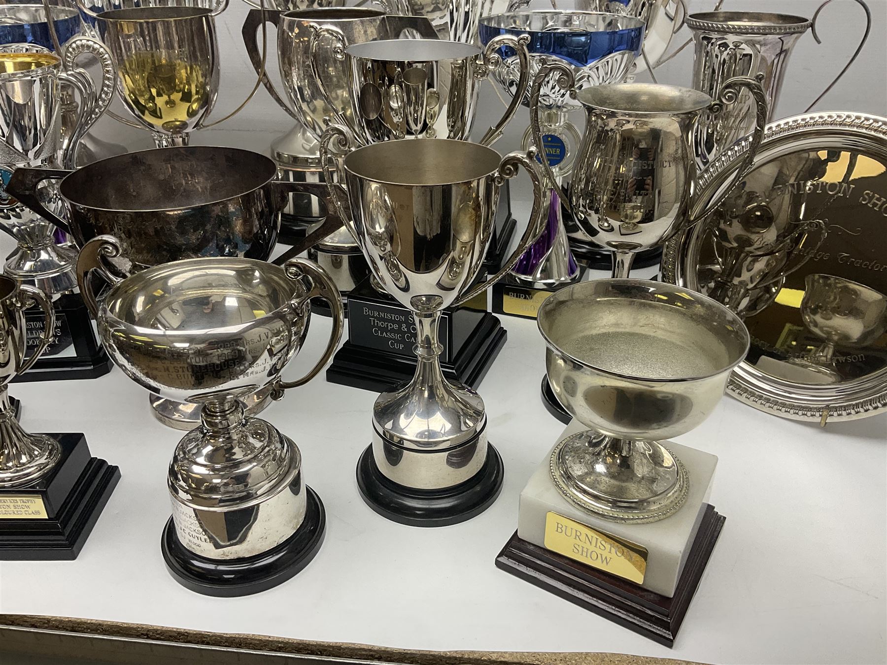 Collection of silver plated and metal trophy cups and winners plaques, all relating to the Burniston and District Show, most engraved with competitions and winner's names, in three boxes 