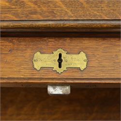 Edwardian oak roll-top desk, the tambour enclosing a fitted interior of pigeonholes and dividers, over a central kneehole flanked by twin banks of drawers with brass handles, on plinth bases