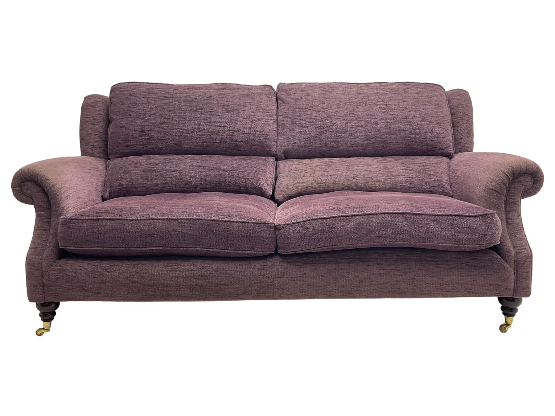 Parker Knoll - pair of large two-seat sofas upholstered in purple fabric, turned mahogany finish front feet with brass cups and castors 