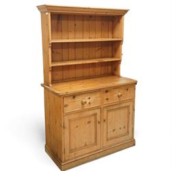Traditional pine kitchen dresser, the open rack with three shelves beneath a moulded top, over a base fitted with two drawers and a pair of panelled cupboard doors, the whole raised on a moulded base