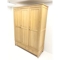 Light oak triple wardrobe, projecting cornice, three doors enclosing fitted interior above one long and one short drawer, stile supports 
