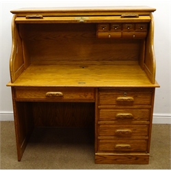  Colonial oak single pedestal shaped roll top desk, fall front frieze drawer with keyboard slide and single cupboard door enclosing fitted interior on plinth base (W123cm, H132cm, D74cm) with an oak swivel chair, turned and carved splat, upholstered seat (W55cm)  