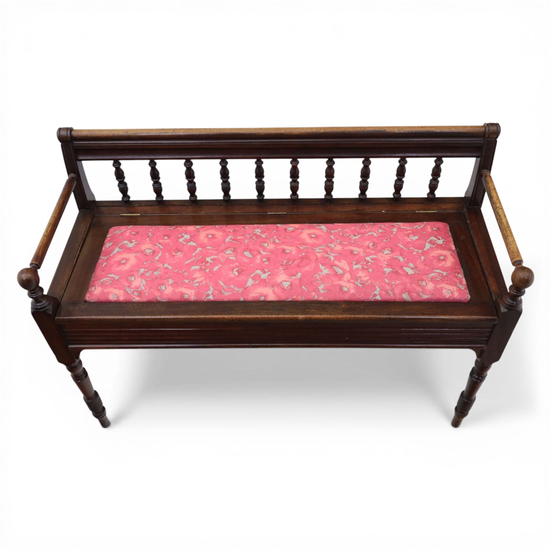 Early 20th century mahogany hall bench, spindle turned back with shaped top rail and open arms terminating in ball finials, upholstered seat within a fluted frieze, raised on turned tapering supports