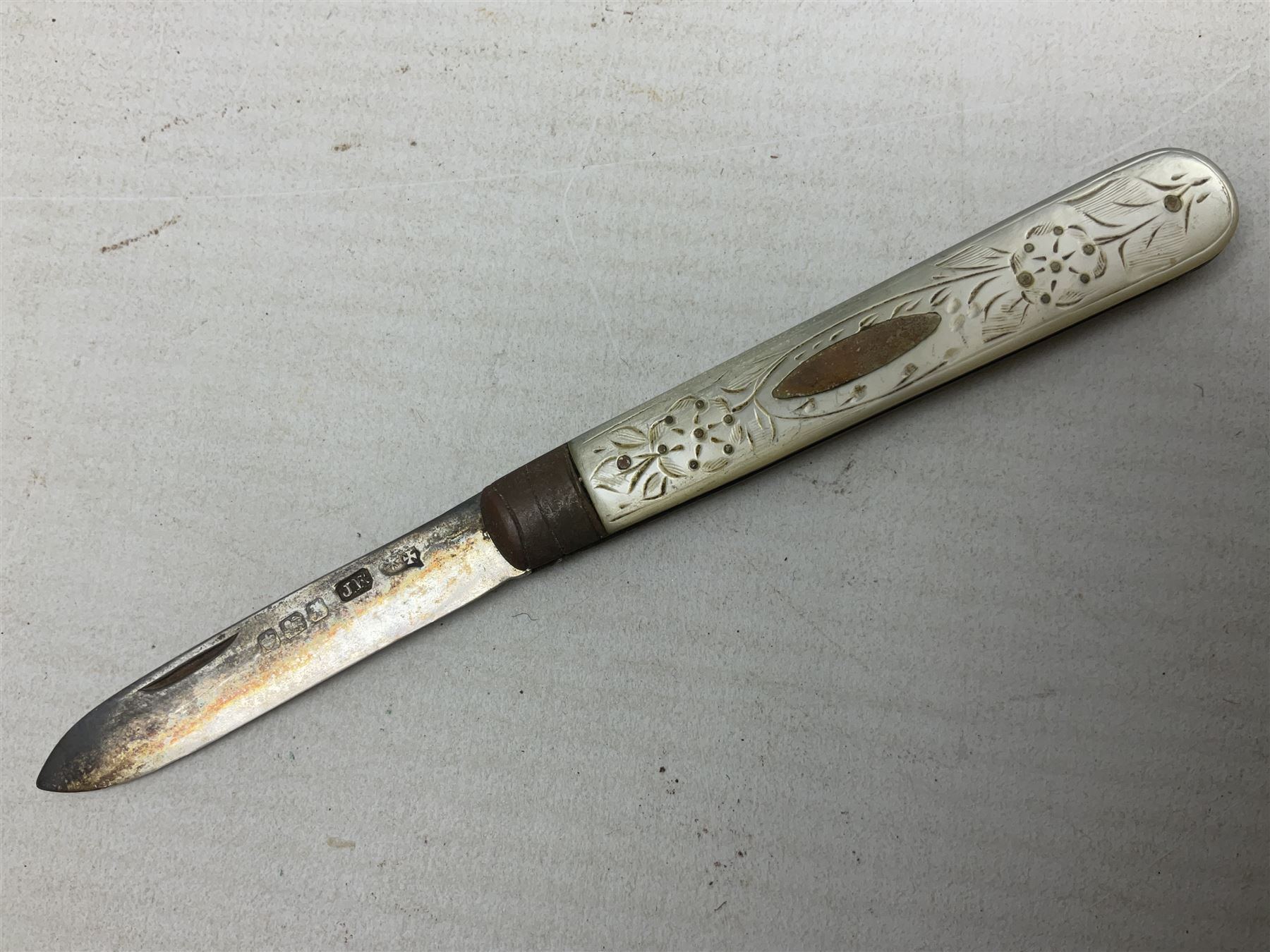 Silver mounted dressing table mirror, embossed with birds, masks, and foliate and C scrolls, hallmarked Birmingham, and fruit knife with mother of pearl handle and silver blade, (2)