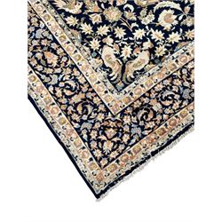 Persian Kashan indigo ground rug, the field consisting of trailing flower head bands and leafy branches, decorated with kuş or bird motifs, the border with repeating border containing curling leaves and flower heads, within guard bands 