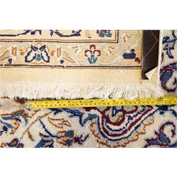 Persian Nain ivory ground rug, the busy oval field profusely decorated with scrolling foliate decoration and palmettes in citrine and indigo tones, the central medallion with matching spandrels, the multiple guard bands with repeating stylised quatrefoil motifs and trailing scrolling foliage and flowerheads