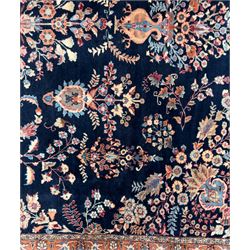 Northeastern Persian Meshed carpet, the deep navy field with a symmetrical floral arrangement of stylised flowerheads, palmettes and scrolling vines issuing from a central urn, enclosed by broad rust and blue borders of floral arabesques and lotus forms, from the region of Meshed
