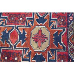 Caucasian pale red ground rug, the field decorated with three large medallions and stylised flower heads, within repeating border 