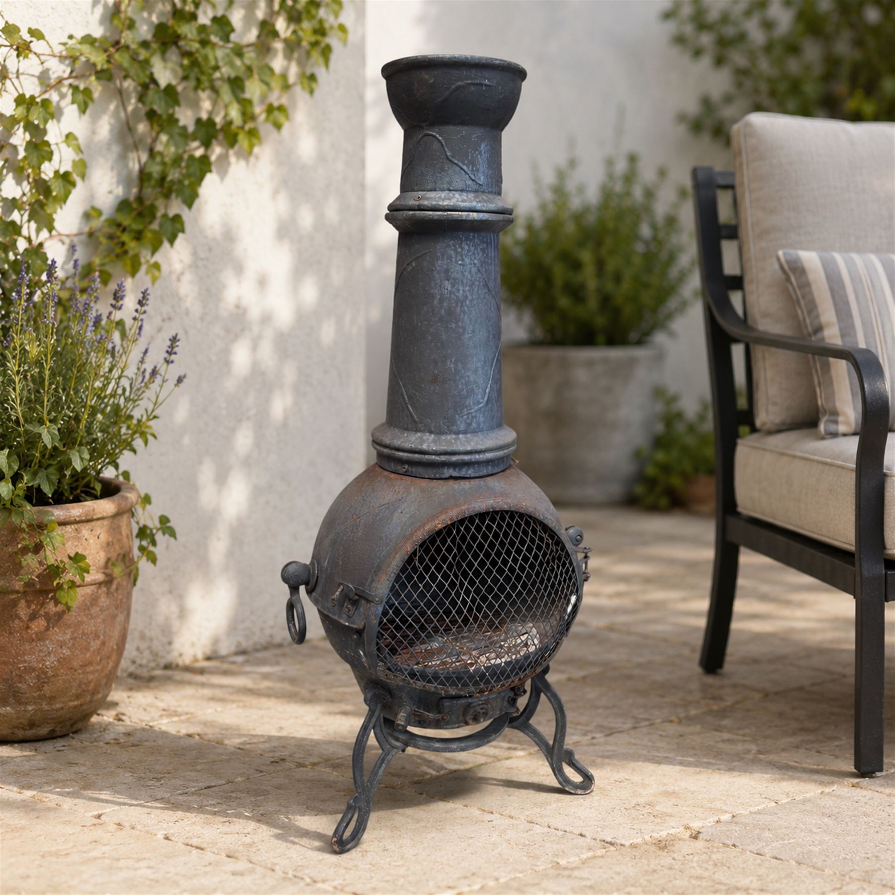 Cast iron garden chiminea, with mesh front spark guard, flue chimney on three splayed legs, finished in black.