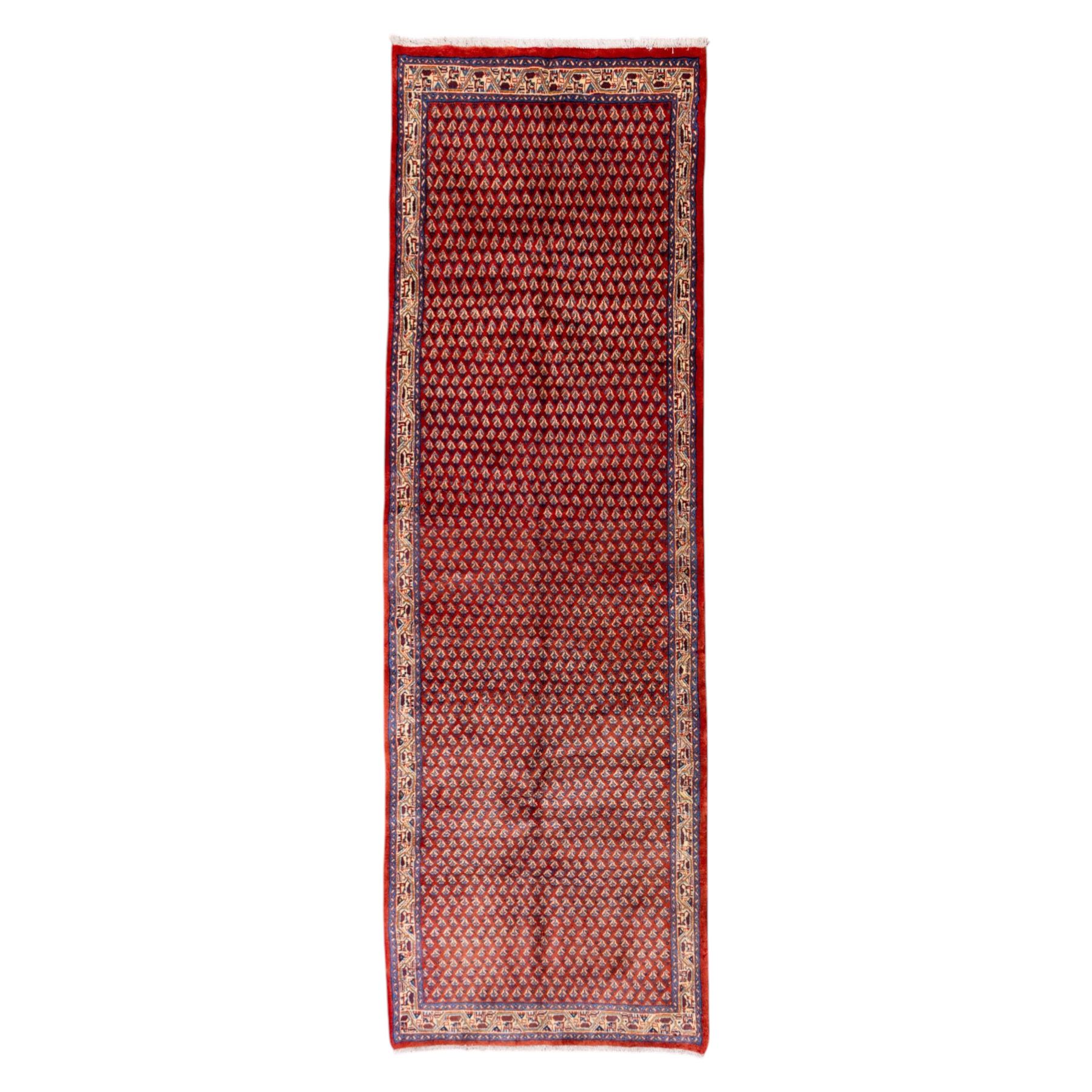 West Persian Saraband (Boteh-Mir) runner madder-red field densely decorated with repeating boteh motifs, arranged in diagonal rows enclosed by a geometric border of stylized motifs, between multiple guard stripes, cotton fringe ends  