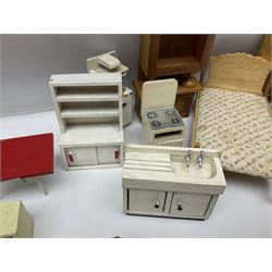 Quantity of wooden doll's house furniture for kitchen, living room and bedroom including chaise longue, longcase clock, bureau, tables, beds, dressing tables, sink unit, cookers etc; various scales; mainly natural wood finish but some painted