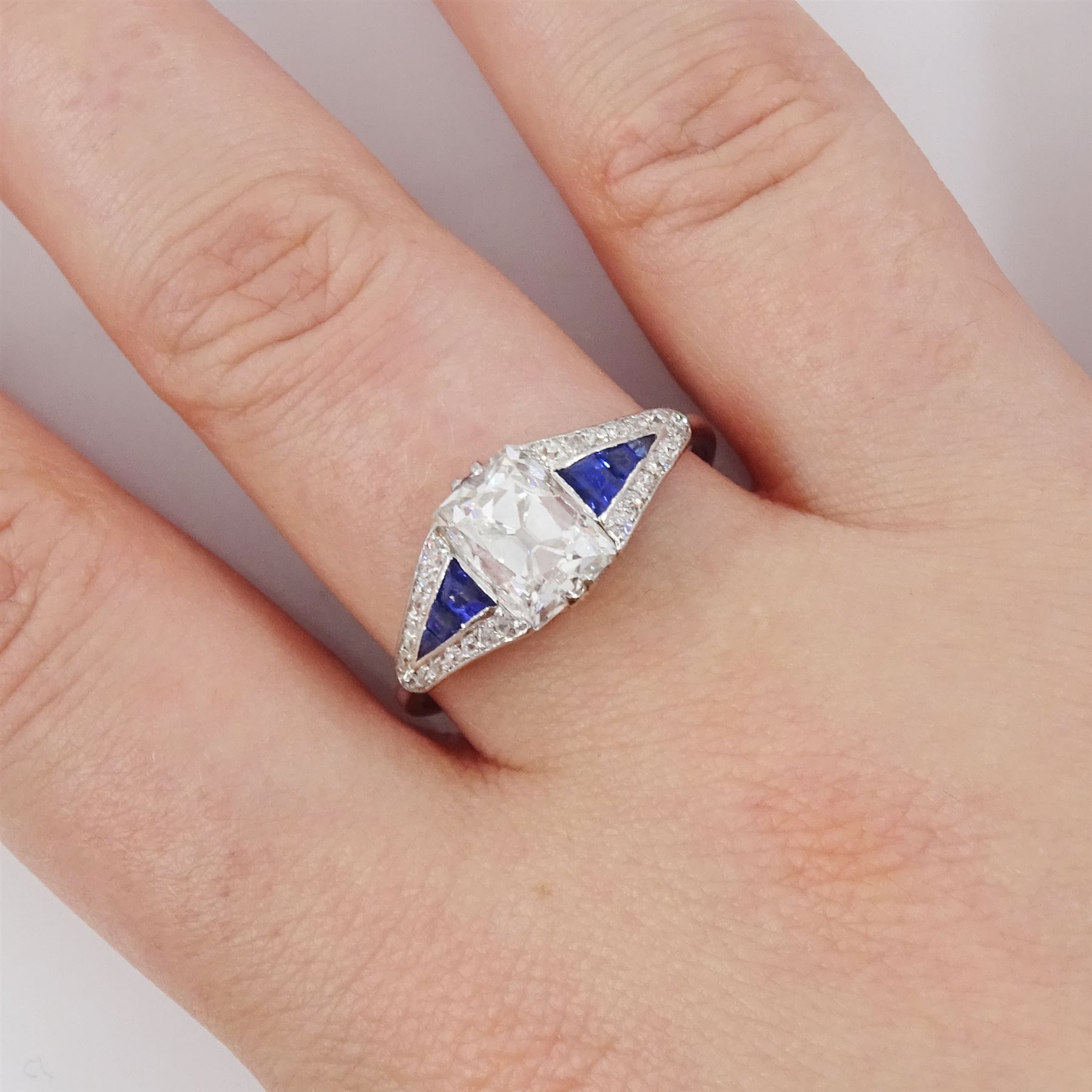 Platinum diamond and sapphire ring, the principal old cushion cut diamond of approx 1.50 carat, each side set with three graduating calibre cut sapphires and old cut diamond surround