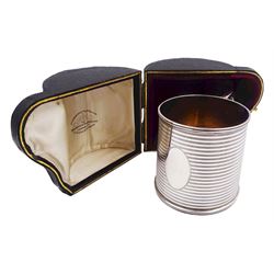Early 20th century silver christening mug, of tapering cylindrical form, with vacant oval panel, horizontal banded decoration, gilt interior and flat topped curved handle, hallmarked Goldsmiths & Silversmiths Co Ltd, London 1915, H6.7cm, contained within original fitted case with burgundy velvet and cream silk lined interior, approximate silver weight 3.75 ozt, (116.6 grams)