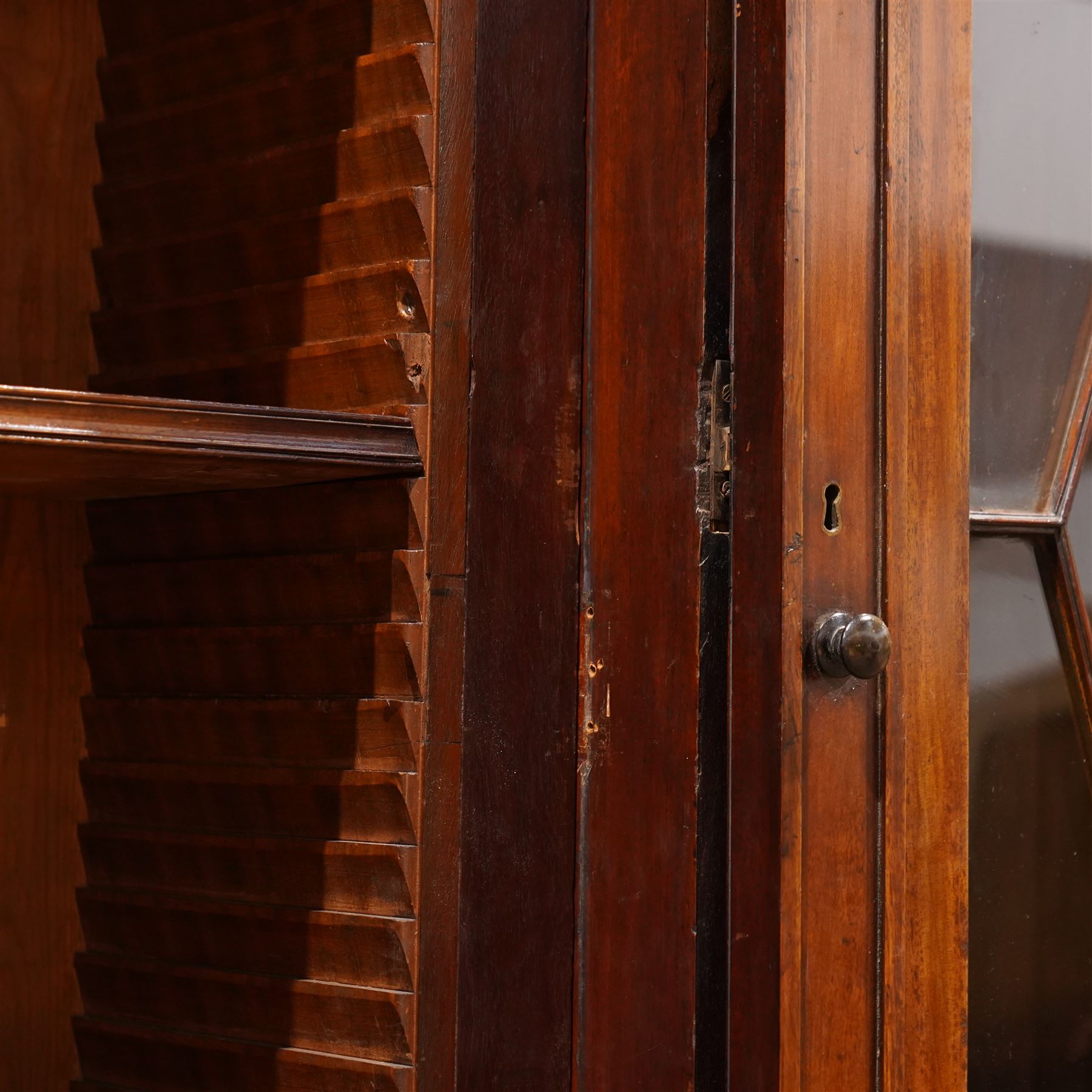 Large Georgian mahogany library bookcase, projecting moulded cornice with row of globular mounts, adjustable shelving enclosed by six astragal glazed doors, fitted with two slides and six panelled cupboard doors, two banks of five drawers, on moulded plinth base; together with two pairs of associated astragal glazed doors in mahogany, from the same property (W55.5cm x H168cm & W48cm x 168cm)