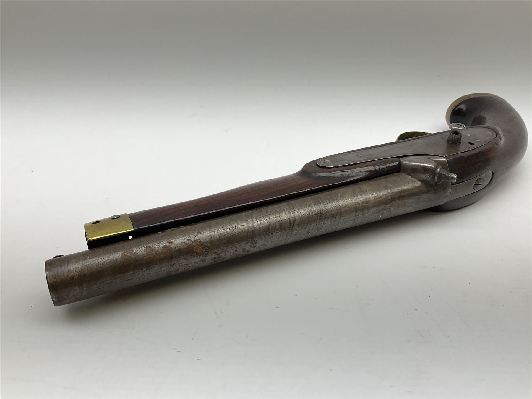 Early 19th century percussion cap cavalry pistol with round 23cm unsighted barrel, borderline engraved action lock (lacking hammer), walnut full stock with heavy brass furniture, iron lanyard ring to the flat butt cap and long flat retaining spring below fore-end for captive ramrod (missing) L41cm overall