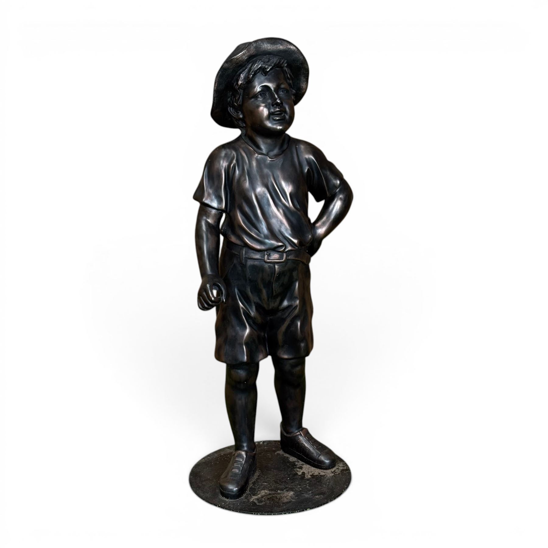 Bronzed composite figure of a boy wearing a hat, on circular plinth