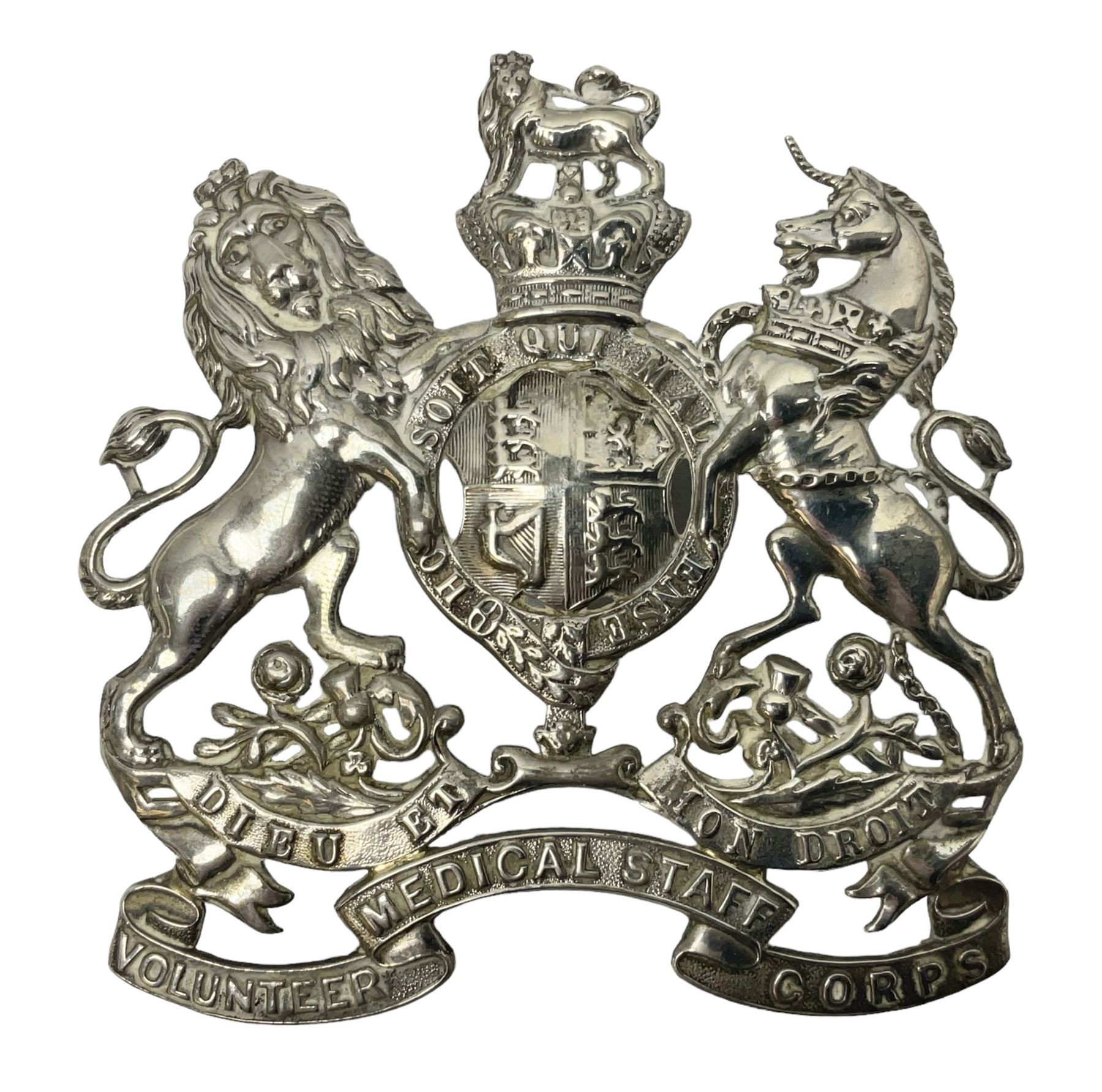 Victorian Volunteer Medical Staff Corps white metal helmet plate in the form of Victorian crowned Royal Arms with three part lower scroll for “VOLUNTEER MEDICAL STAFF CORPS”; three lug fittings to the reverse L8.5cm