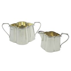 Edwardian silver twin handled sucrier, and cream jug, each of lobed oval form with oblique gadrooned rim, hallmarked Walker & Hall, Sheffield 1904 and 1907, approximate total silver weight 8.61 ozt (268 grams)