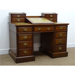  Edwardian oak twin pedestal Dickens style desk, brass gallery, four trinket drawers flanking hinged sloping writing pad, three piece green tooled leather inset top, nine drawers, plinth base,  retailed by Rowntree's of Scarborough, with keys, W123cm, H100cm, D71cm  