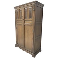 Mid-20th century Jacobean design medium oak double wardrobe or hall cupboard, enclosed by two panelled doors carved with Gothic design tracery 