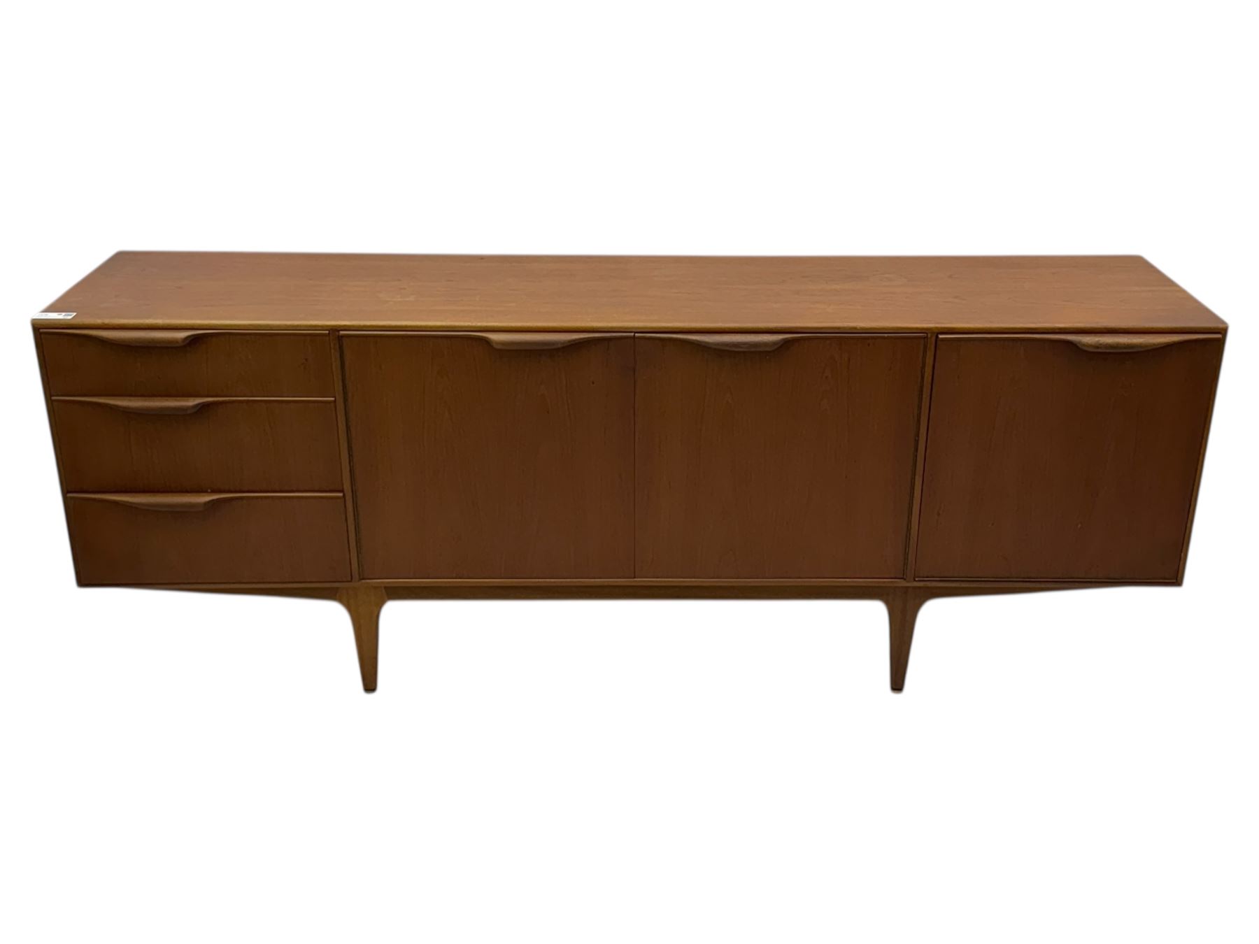 Tom Robertson for AH McIntosh & Co of Kirkaldy - mid-20th century teak 'Dunvegan' sideboard, with three graduating drawers fitted cutlery divider, three cupboards one fall front each with recessed sculptural handles, raised on shaped and tapering supports