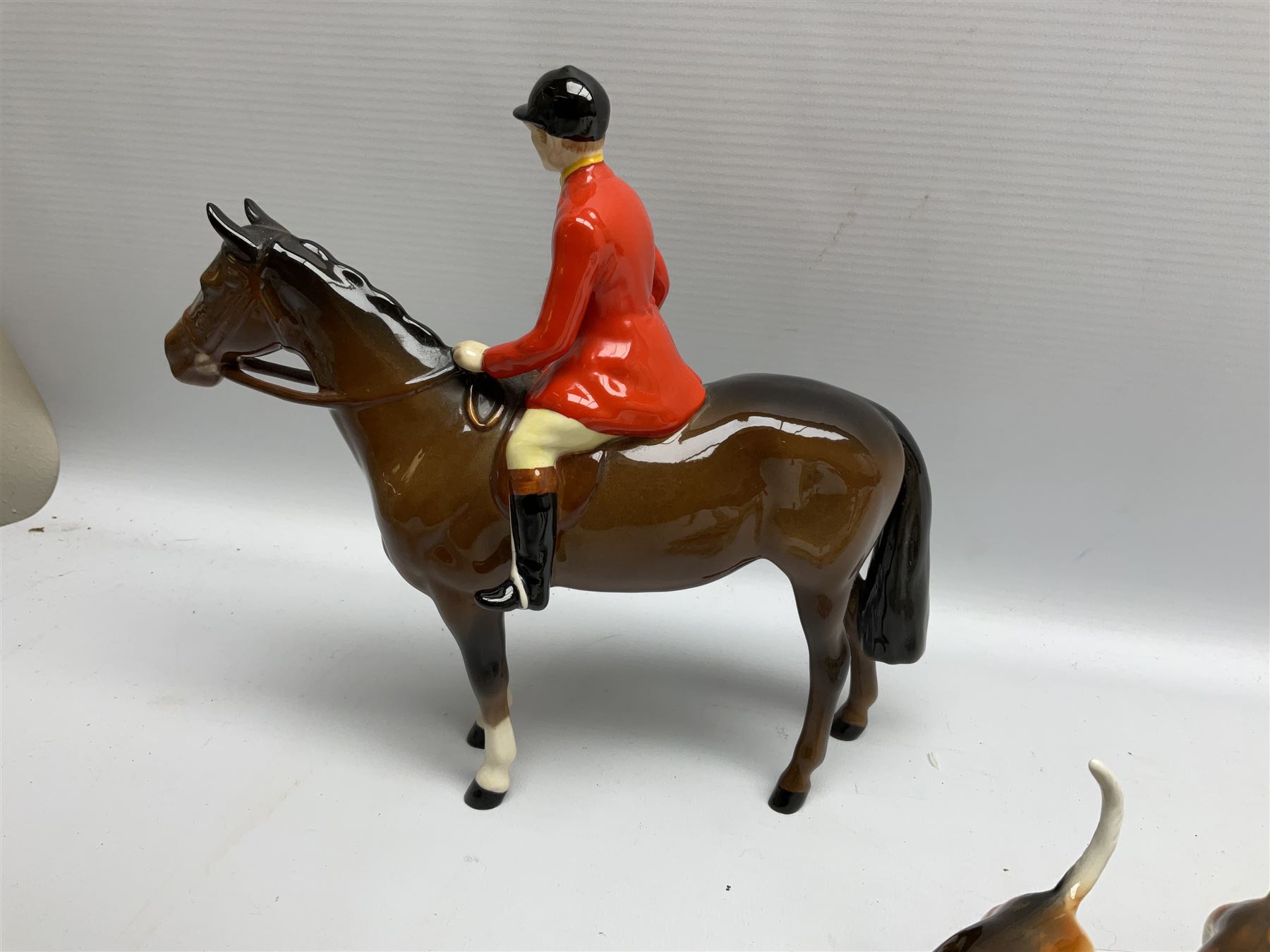 Beswick hunting group, comprising huntswoman on grey horse no 1730, huntsman on brown horse no 1501, two seated fox figures no 1748 and seven fox hounds, all with printed marks beneath (11)