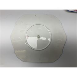 Shelley Strand shaped tea wares, decorated with blue and pink daisies upon a white ground, comprising four teacups, four saucers, three tea plates, milk jug, sugar bowl and cake plate, all with printed green mark beneath and painted pattern no 12216