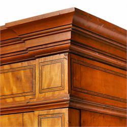 Victorian neoclassical style satinwood triple-section wardrobe, the central mirror section and arched pediment with carved monogram flanked by two panelled crossbanded doors, revealing two drawers and grooves for shelves, the hanging cupboards each with a single drawer, the whole supported on a plinth base