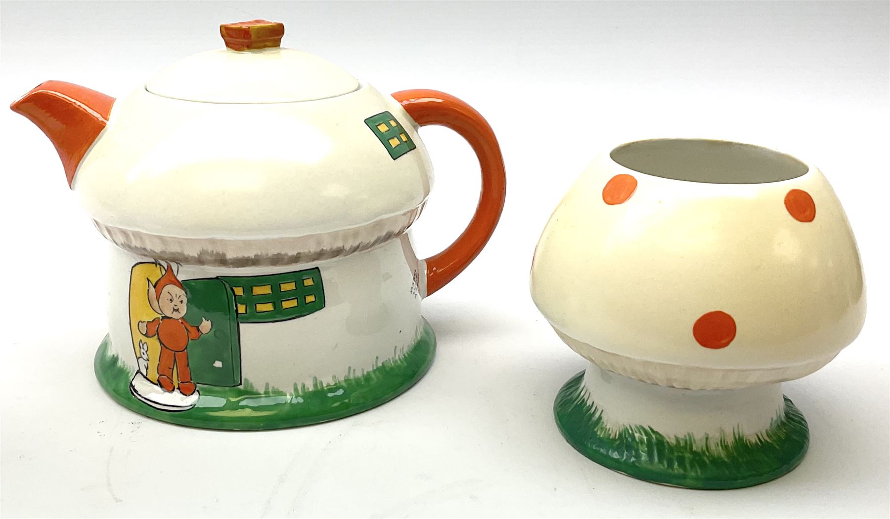 Shelley Boo Boo three piece tea set designed by Mabel Lucie Attwell, comprising teapot modelled as a house, sugar bowl modelled as a toadstool, and creamer modelled as an elf, each with printed marks beneath, together with a Shelley Mabel Lucie Attwell teacup and saucer. 