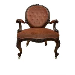 Victorian walnut framed open armchair, cresting rail decorated with cared roses and folate, back and sprung seat upholstered in buttoned coral rose fabric, scrolled arm terminals, raised on cabriole supports with ceramic castors