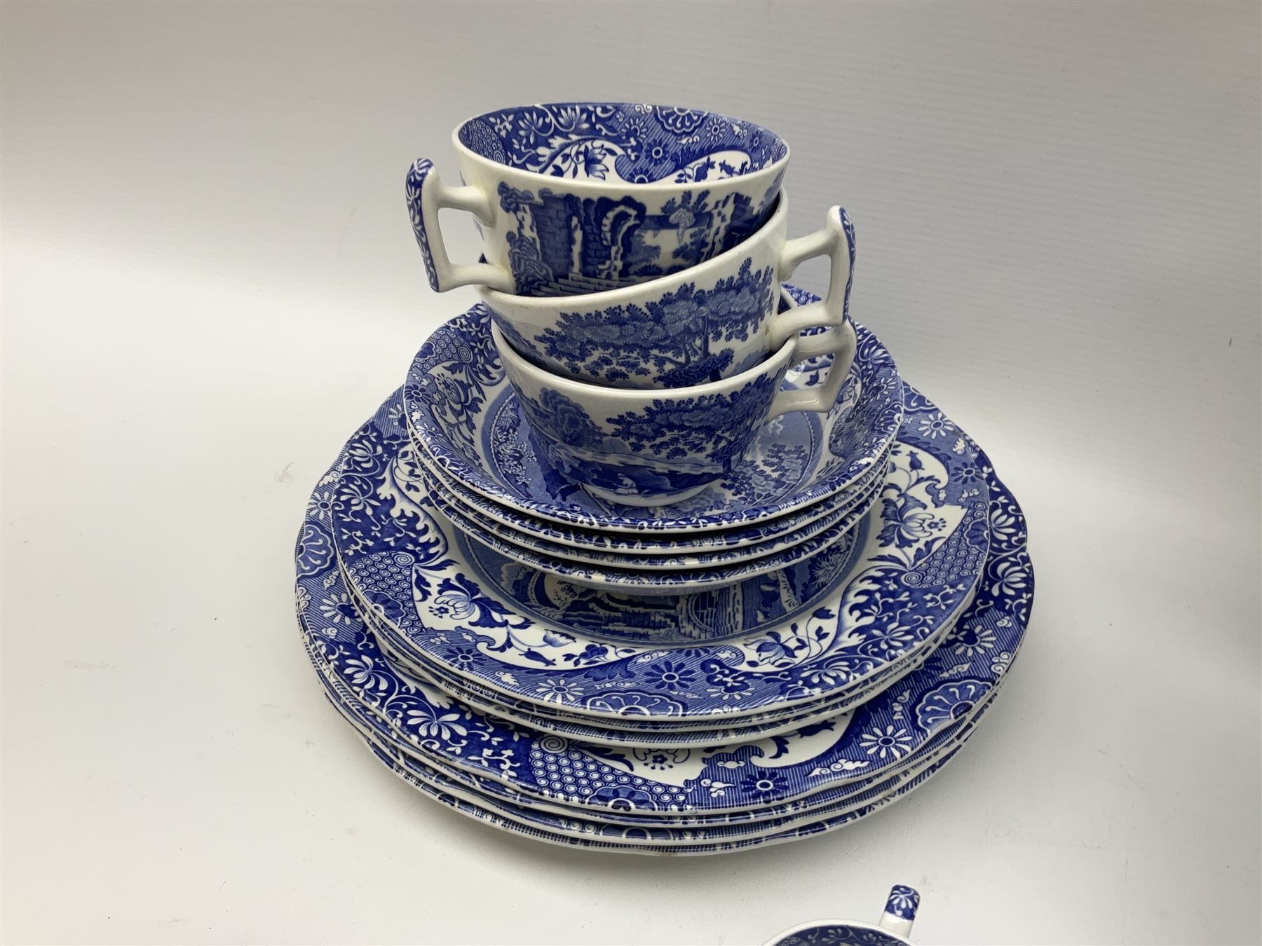 Spode blue and white Italian pattern dinner and tea wares, comprising five dinner plates, four side plates, seventeen side plates, four bowls, ten tea cups and twenty one saucers, five coffee cans and six saucers, and a flan dish, with blue and black printed marks beneath 