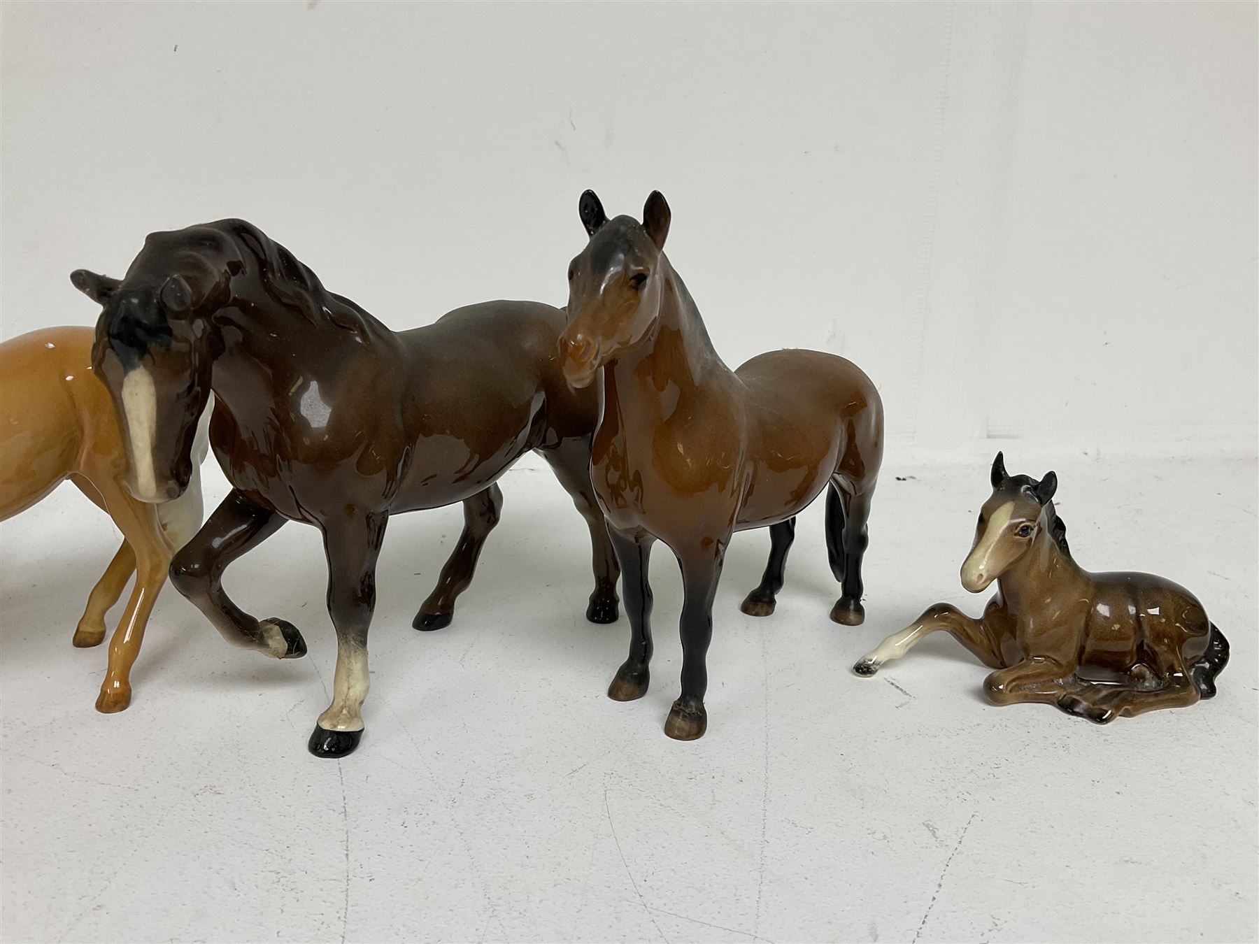 Group of Beswick figures of horses, to include a Palomino horse, Bay Shire horse, recumbent bay foal etc, all with printed marks beneath (5)