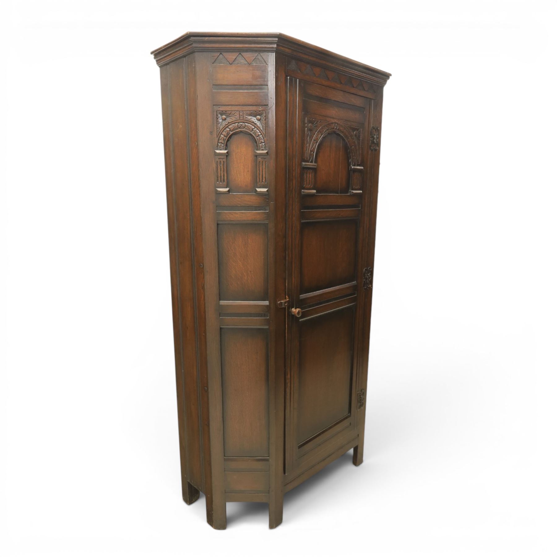 20th century dark stained oak hall robe, cantered sides enclosing a hooks and a shelf, panelled and carved sides, raised on stile supports