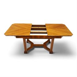Art Deco walnut extending dining table, book-matched veneered shaped top, raised on cluster-column supports, united by stretchers, additional leaf extends to 185cm  