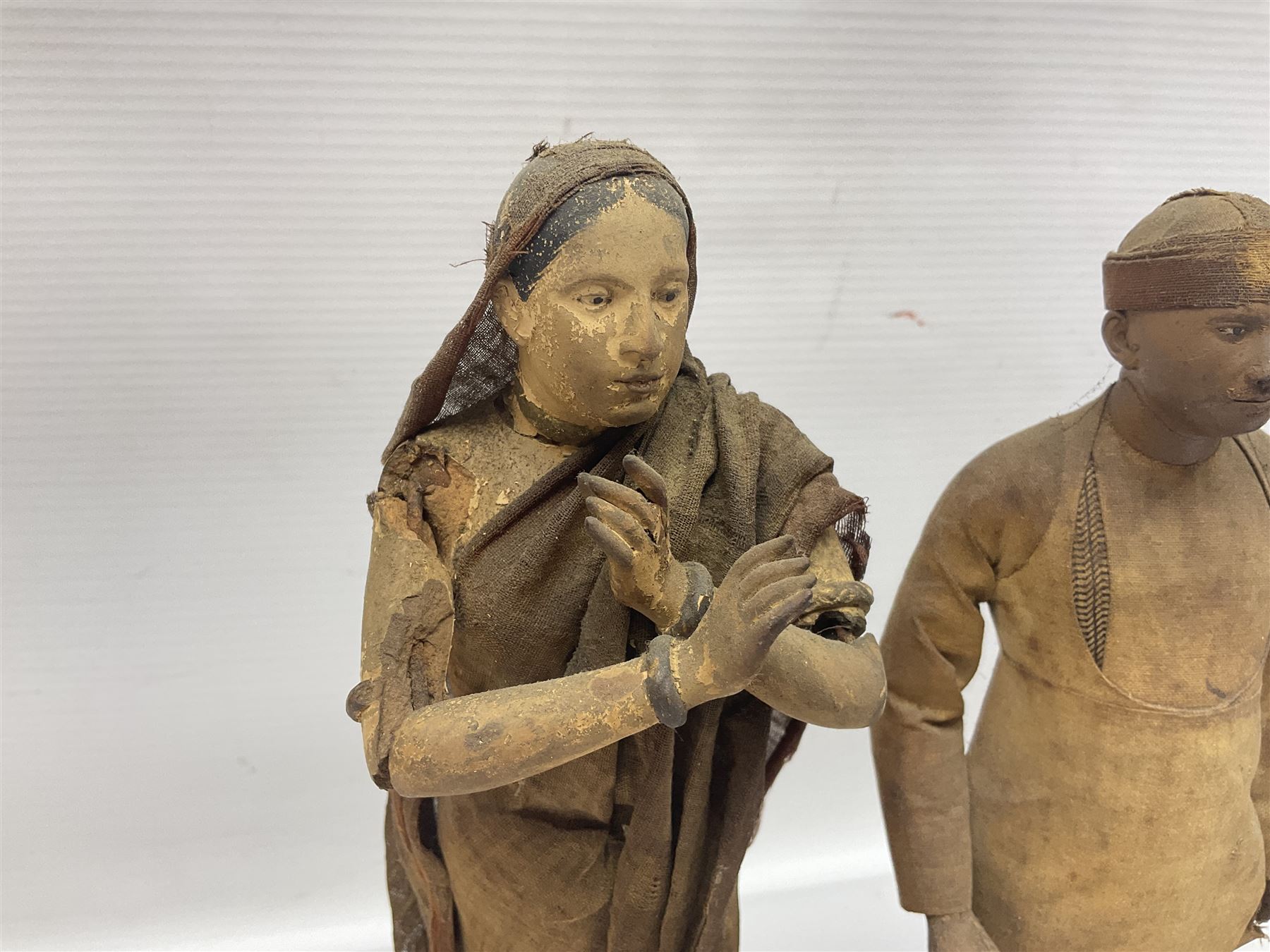 Seven 19th Century Indian clay dolls, possibly Krishnanagar, each figure with painted details, wearing cloth garments, standing on rectangular bases, some with paper label to the base, H25cm