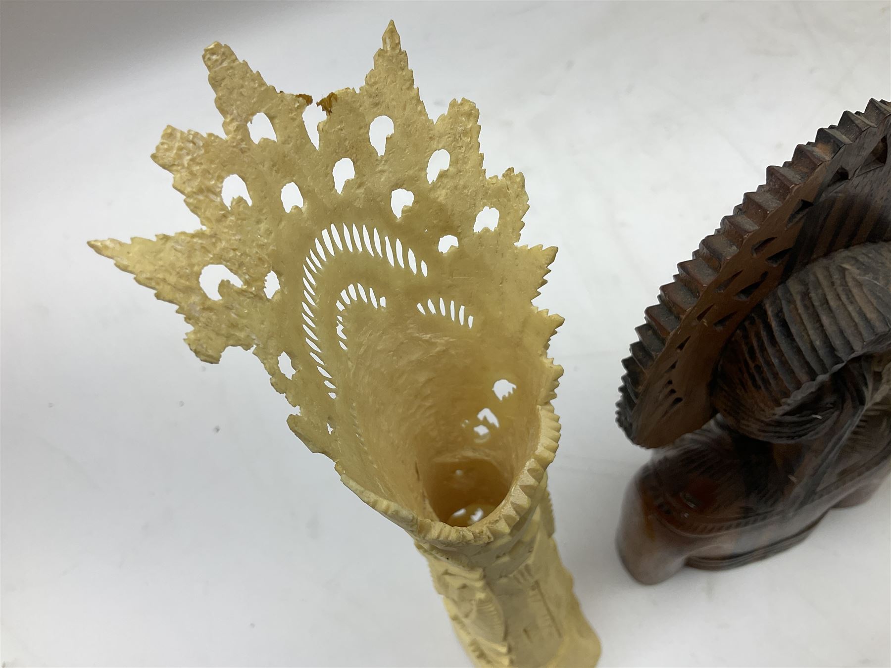 Hardwood bust of an Indoniesian Goddess, carved wearing a pierced headdress, from Klungkung, Bali, H20cm, together with a pair of bone carvings of deity figures, and a carved wood Netsuke in the form of a Chinese dragon