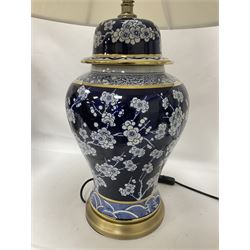 Pair of blue and white table lamps, each of baluster form, decorated with prunus blossom, within stylised borders, raised upon circular gilt base, excluding fittings H48cm