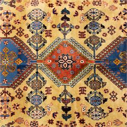 South Persian Yallameh hand-knotted rug, ivory ground, with a central stepped pole medallion design in blue and terracotta tones, surrounded by geometric tribal motifs incorporating stylised flowerheads, birds, hooked devices and angular vine work, enclosed by dark navy spandrels and a terracotta border with repeating geometric motifs, flanked by narrow patterned guard stripes, with cotton fringes