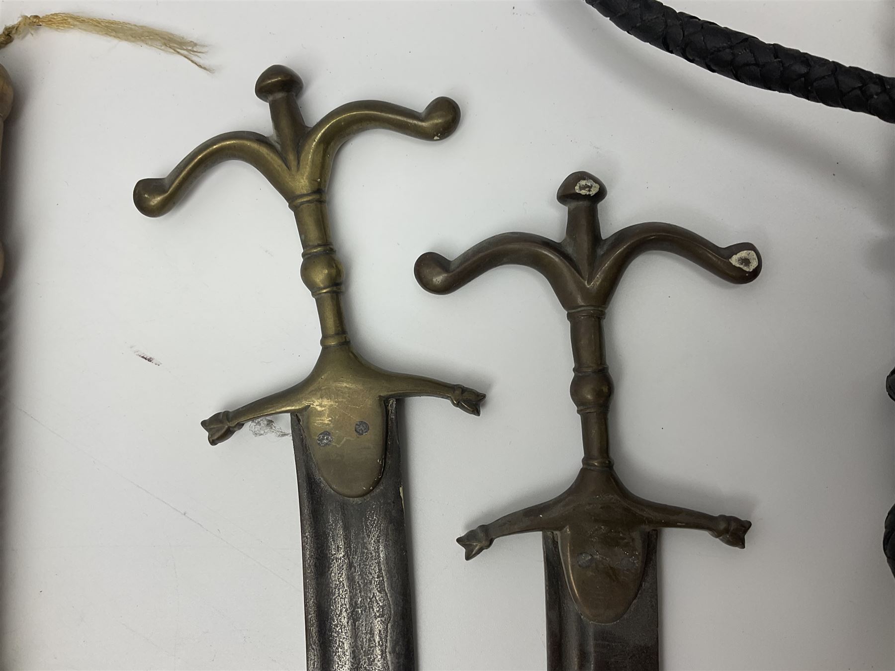 Near pair of short swords each with slightly curving 41cm fullered steel blade and all brass H-shaped hilt L52cm overall; plaited black leather whip; and reproduction pair of brass hilted swords, brass halberd blade and mace (7)