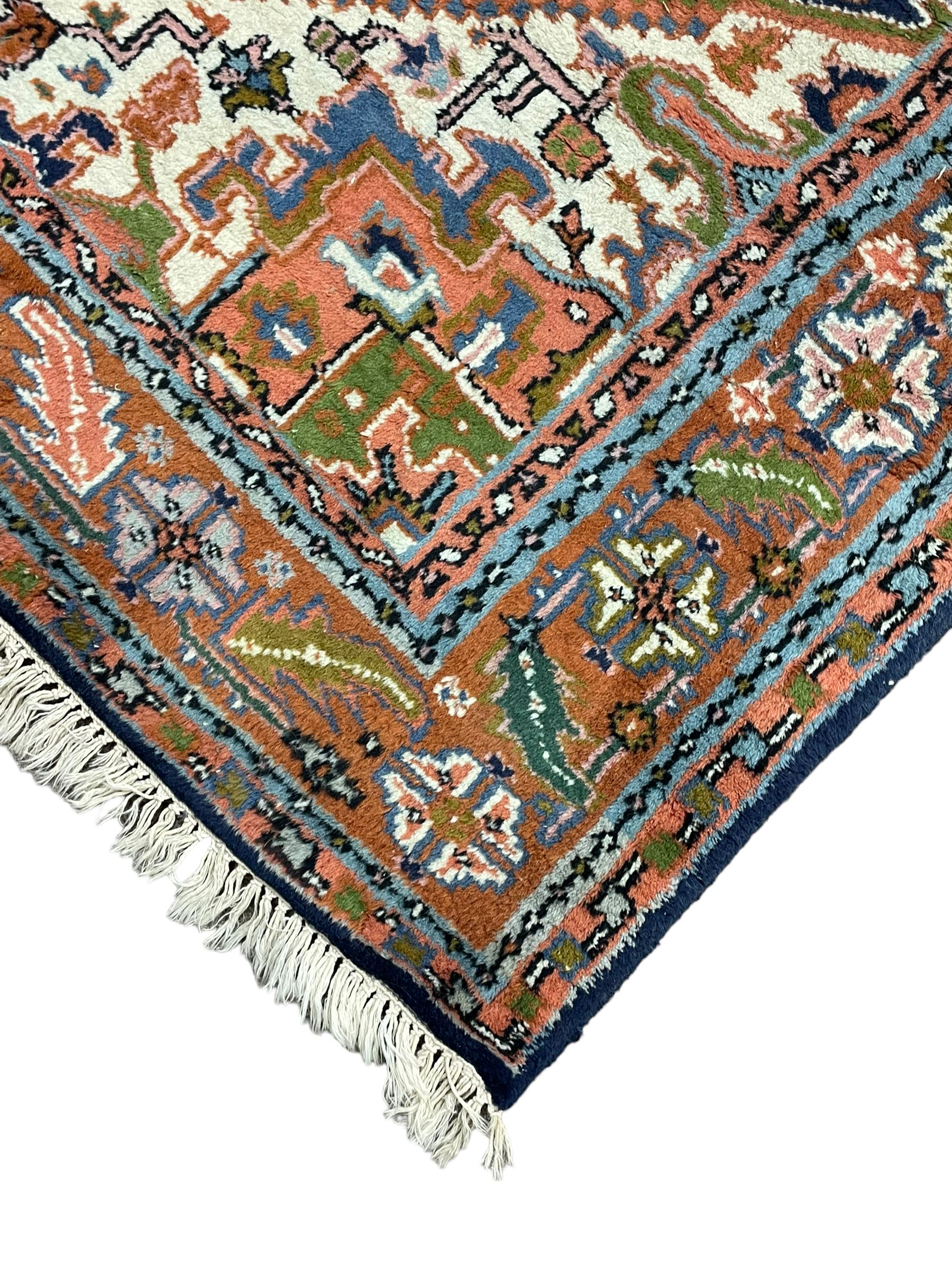 Persian Heriz indigo and rust ground rug, central geometric star medallion decorated with stylised foliate motifs, the border decorated with stylised flower heads