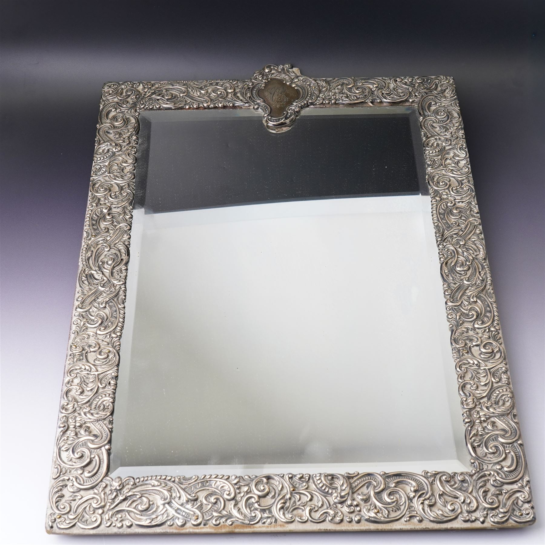 Late Victorian silver mounted dressing table mirror, the frame decorated with scrolls and oval cartouche initialled 'C', bevelled plate on an easel stand 57cm x 38cm London 1899 Maker Charles Henry Dumenil 