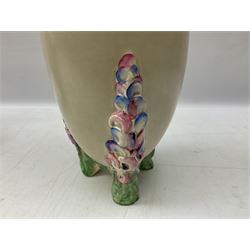 1930s Carlton Ware Art Deco Garden pattern vase of shouldered ovoid form, decorated with blue, pink and yellow flower heads on a mottled blue and white ground, pattern no. 3413, with printed and painted marks beneath, H19cm, together with a Clarice Cliff My Garden pattern vase, raised upon three feet with blue, pink and purple moulded Hollyhock design, H20cm, with Clarice Cliff Wilkinson Ltd England marks beneath