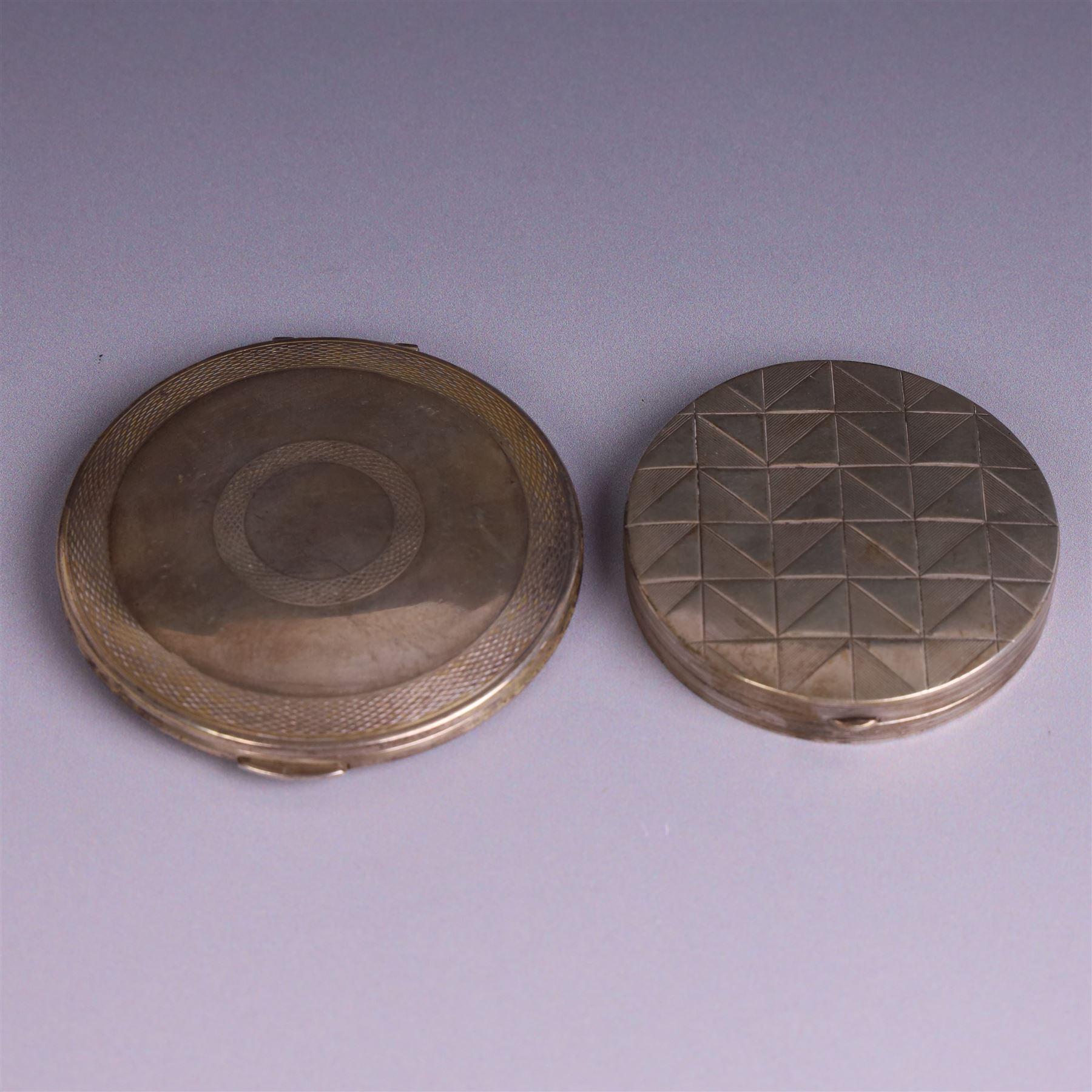 Two silver circular compacts, including Continental 800 silver example with geometric decoration, stamped 800 and a Kigu example with engine turned concentric circle decoration, hallmarked Kigu Ltd, London 1963, largest D7.5cm