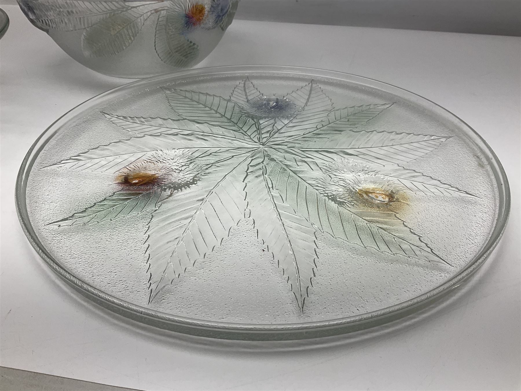 Two French pressed glass bowls of shallow circular form, relief moulded with flowers and foliage, together with a matching charger, largest bowl D34cm  